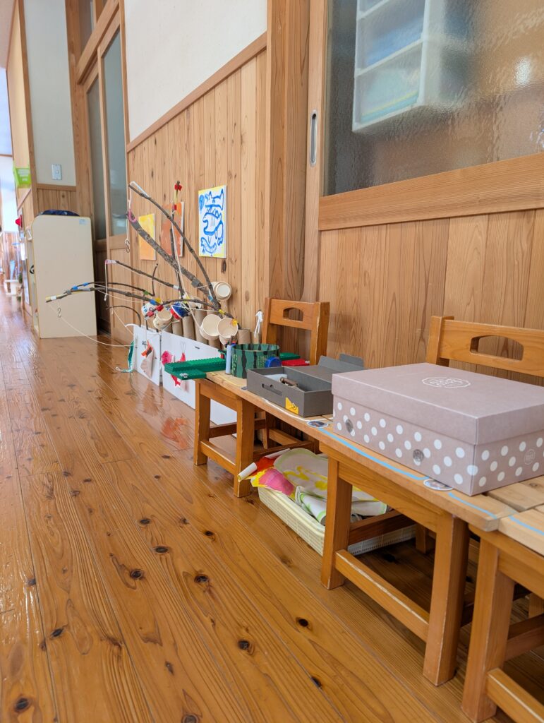 木造の廊下の一角。小さな木の椅子を並べた棚の上に、子どもたちが作った釣り竿や空き箱を利用した制作物が並んでいる。